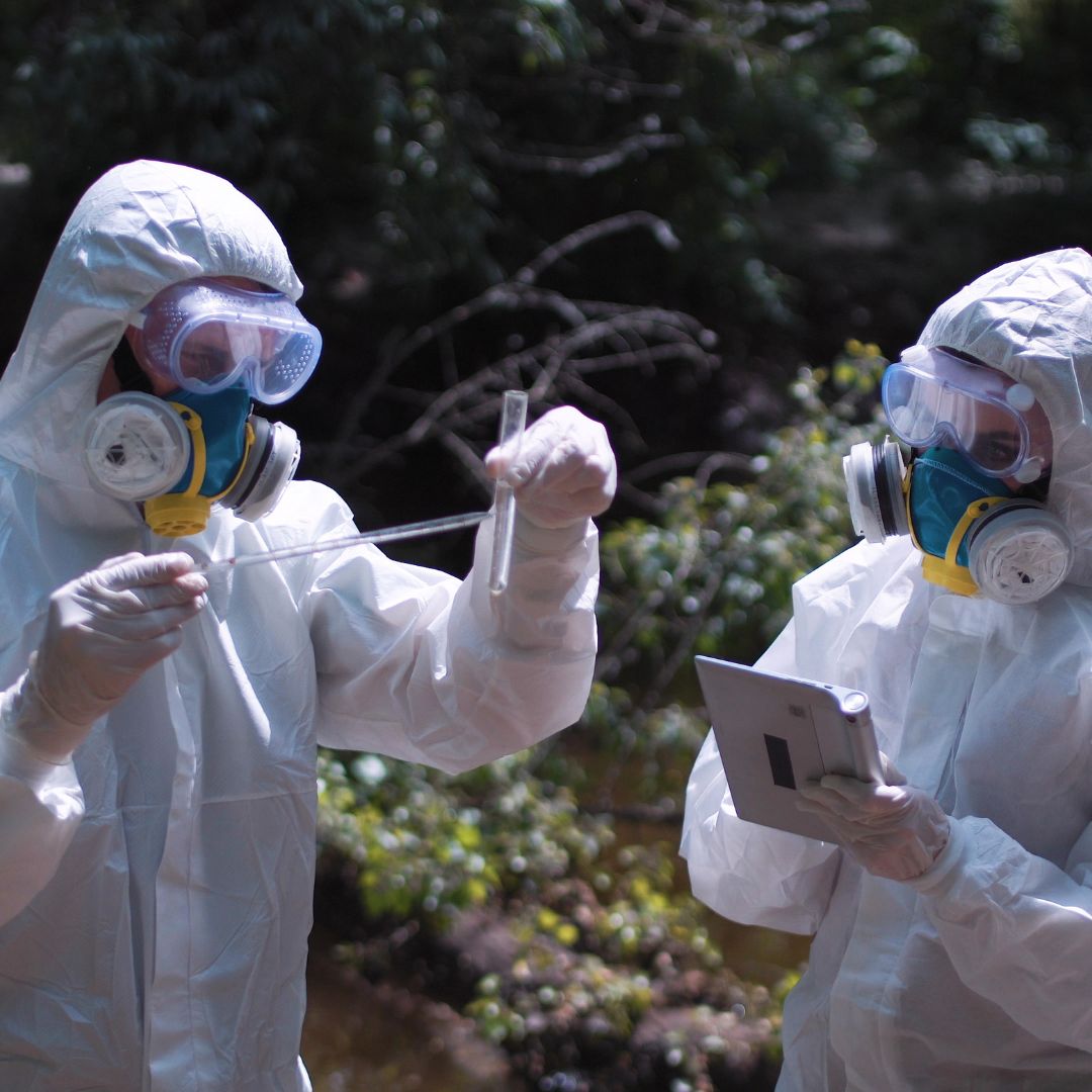 people in safety gear inspect liquid in tube 